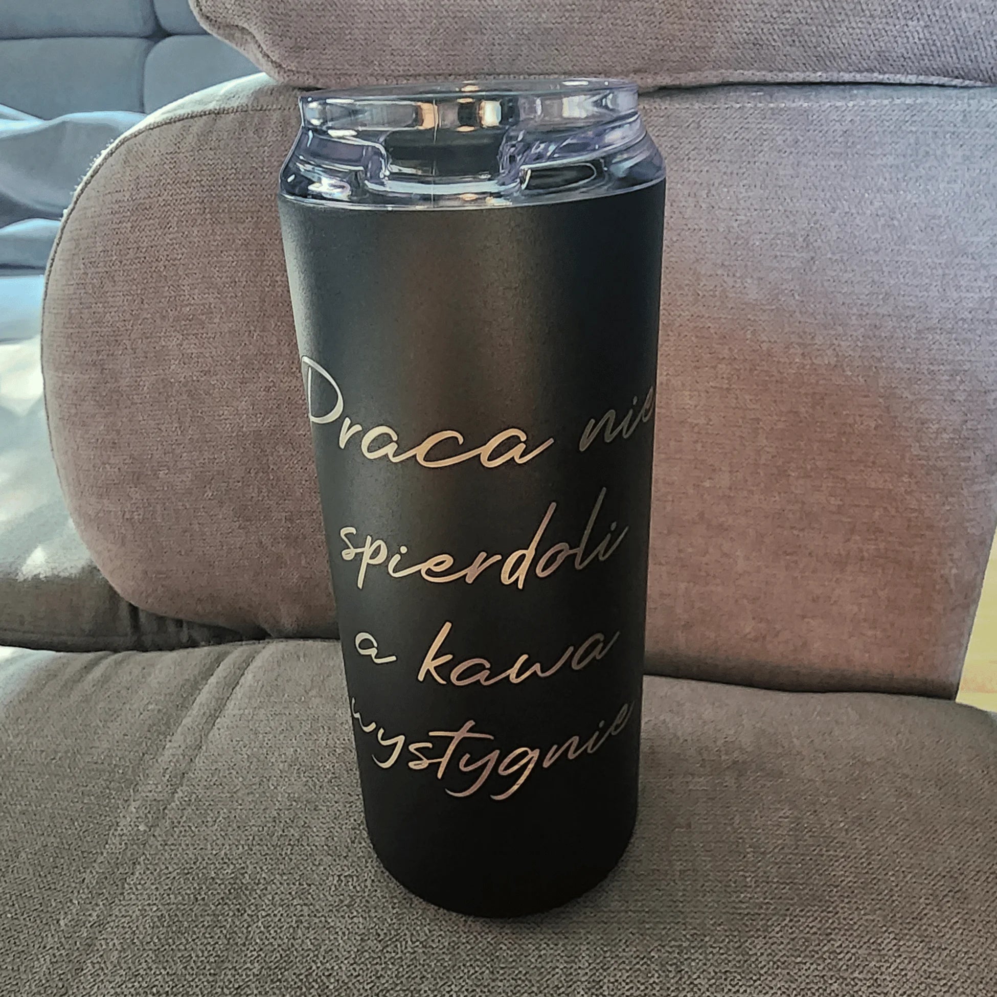 Black tumbler with gold text on a brown couch