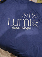 Blue shirt with 'Lumi Studios + Shoppe' logo on a blue background