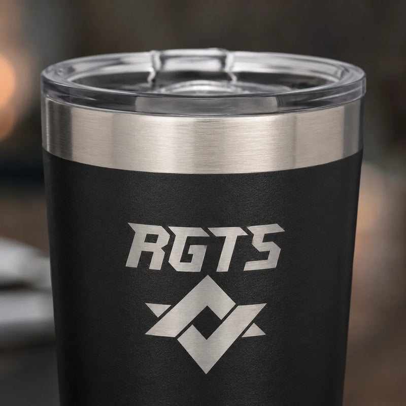 A close-up of a black insulated tumbler with a clear lid, featuring a brushed silver stainless steel band near the top and a silver etched logo that reads 'RGTS' with a geometric emblem below it.