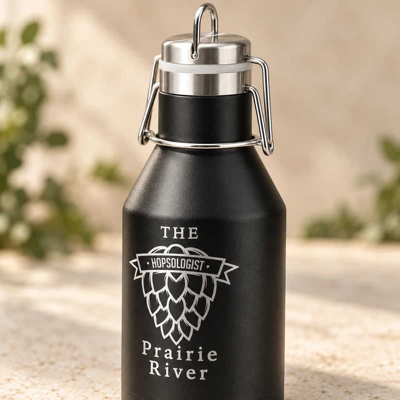 A matte black insulated growler bottle with a stainless steel swing-top lid, featuring a white engraved hop cone logo and the text 'THE HOPSLOGIST' and 'Prairie River'.