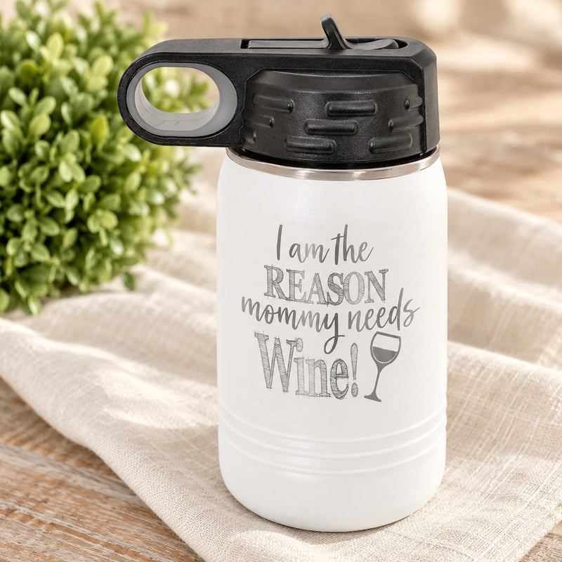A white insulated water bottle with a black lid and a gray printed slogan reading 'I am the REASON mommy needs Wine!' with a wine glass icon, styled on a beige cloth with a green plant in the background.