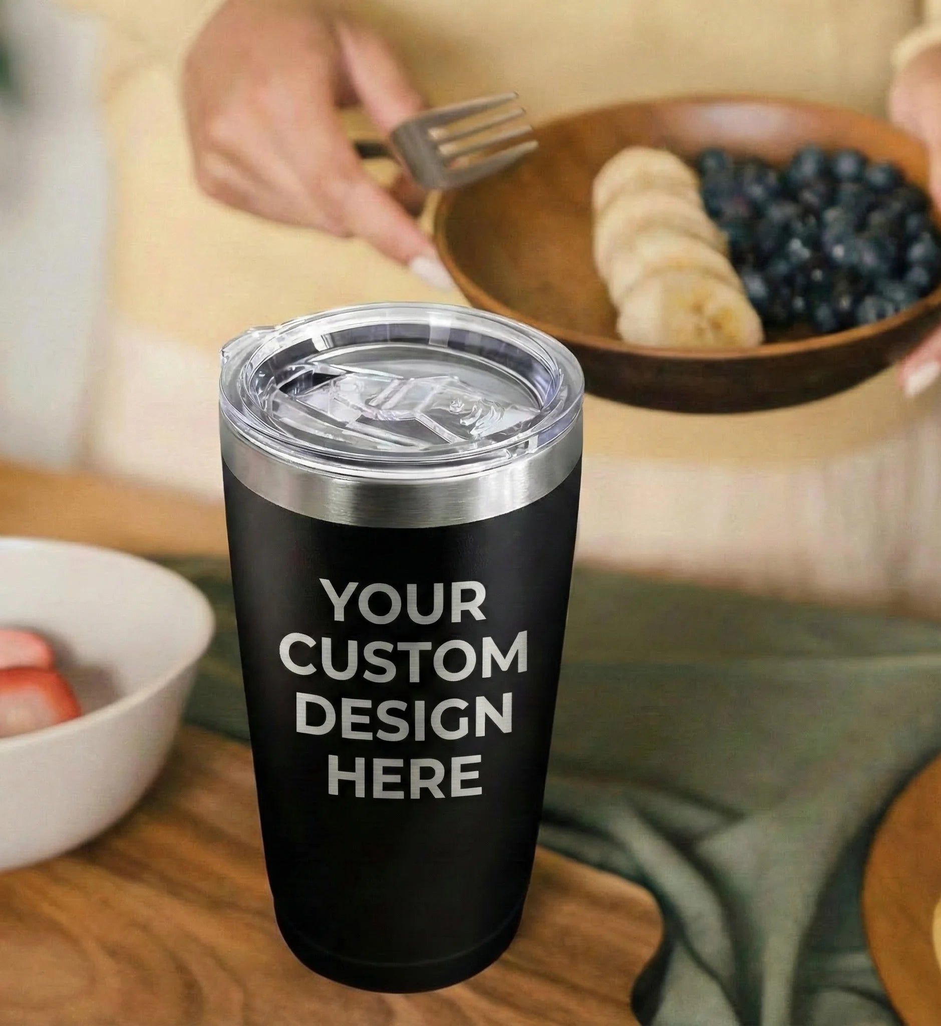 Black tumbler with 'Your Custom Design Here' text in a kitchen setting with fruit bowls.