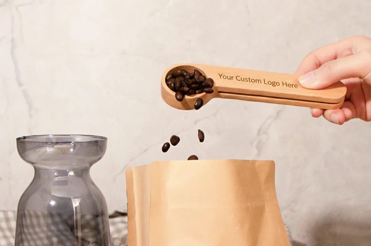 Wooden coffee scoop with engraved text being used to pour coffee beans into a container.